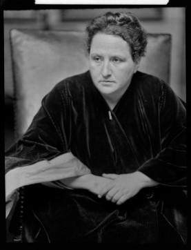 Gertrude Stein seated, arms crossed.