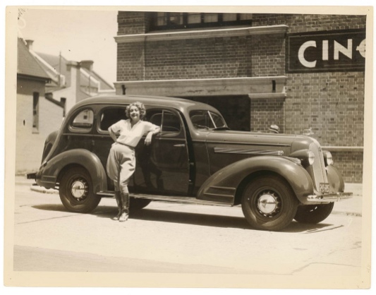 Woman leaning casually against a car.